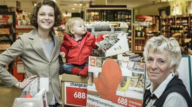 Die Berlinern Caroline Rosales (l) mit Söhnchen Maxime neben einer Verkäuferin an der Kasse eines Supermarktes in Berlin. Fot