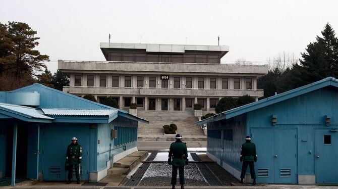 Südkoreanische Soldaten stehen Wache in der Demilitarisierten Zone. Die Hütten stehen mitten auf der Grenze, die mit dem schmalen dunklen Strich markiert ist. Das Gebäude hinten gehört zu Nordkorea. Foto: dpa