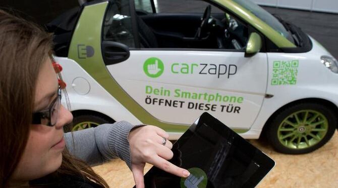 Eine Mitarbeiterin der Firma carzapp demonstriert, wie man mit einem Tablet oder Smartphone die Tür eines »geteilten« Autos ö