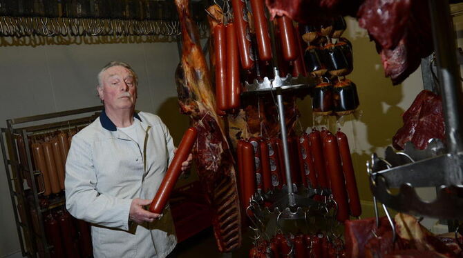 Der Pferdemetzger Rolf Beerwart hält in Waiblingen in seinem Kühlraum eine Wurst in der Hand.