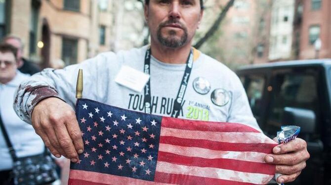 Ein Marathon-Zuschauer hält eine blutdurchtränkte US-Flagge. Foto: Jeremiah Robinson/Zumapress