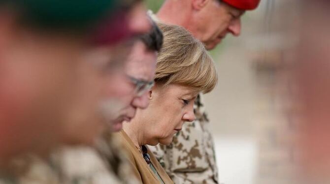 Kanzlerin Merkel und Verteidigungsminister de Maiziere (3.v.r.) gedenken den gefallenen Soldaten der Bundeswehr. Foto: Kay Ni