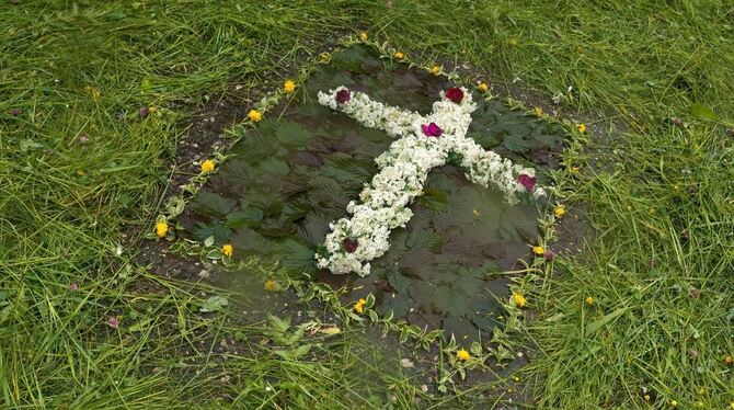 Ein Blumenkreuz mit Grasumrandung liegt an Fronleichnam in der Einfahrt eines Hofes in Seehausen am Staffelsee (Bayern). Fronlei