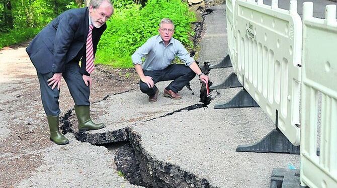 Mit Sorge beobachten Bürgermeister Rudolf Heß und Stadtbaumeister Karl-Jürgen Oehrle die Schäden am Elisenweg. An dieser Stelle ist die Spalte 1,40 Meter tief. GEA-FOTO: SCHÖBEL