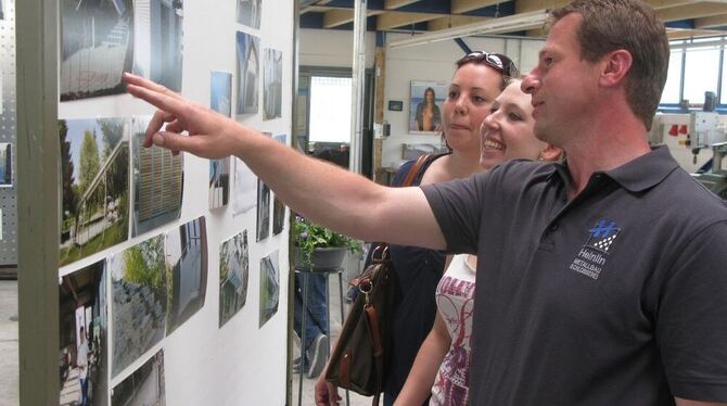 Andreas Heinlin erläutert interessierten Besucherinnen die Bilderausstellung über die Arbeiten seines Unternehmens. 	FOTO: SEITZ