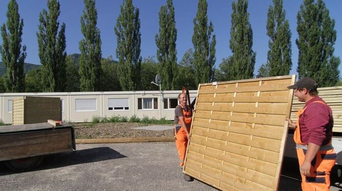 Zwei Mitarbeiter des Bauhofs stellen im August 2013 SChutzwände vor den Containern der Asylantenunterkunft in Dettingen auf. GEA