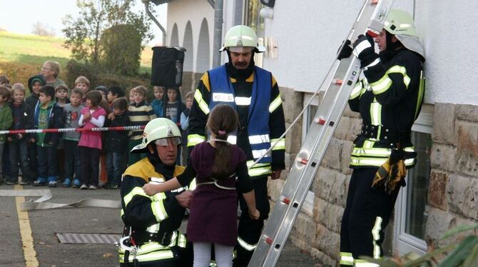 Jeder Handgriff sitzt: Über eine Leiter holen die Feuerwehrmänner ein junges Mädchen aus dem verqualmten Klassenzimmer. Per Nebe