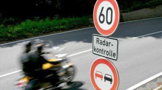 Ein Motorradfahrer fährt an einem Schild mit der Aufschrift »Radarkontrolle« vorbei.