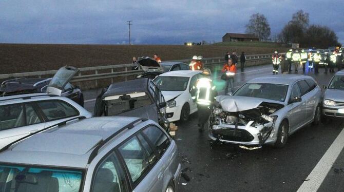 Nach einem Massenunfall auf der Autobahn A81 zwischen Stuttgart-Zuffenhausen und Stuttgart-Feuerbach stehen Helfer neben besc