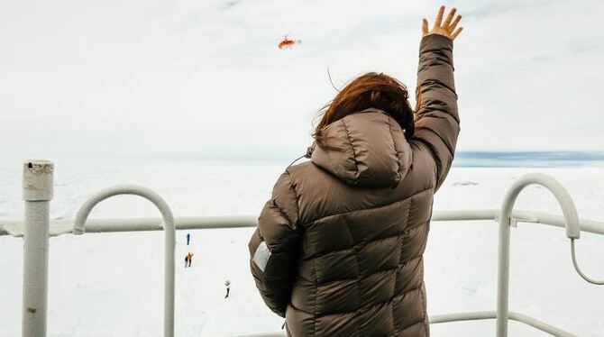 Von Bord der »Akademik Shokalskiy« aus winkt eine Frau einem Hubschrauber zu. Foto: epa/Andrew Peacock / FOOTLOOSEFOTOGRAPHY