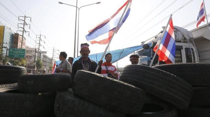 Demonstranten stehen in Bangkok hinter einer Barrikade aus Reifen. Foto: Narong Sangnak