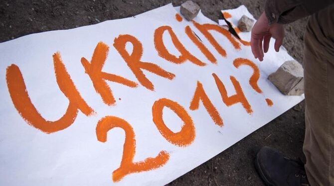 Ein Demonstrant legt ein Plakat mit der Aufschrift »Ukraine 2014?« vor der Russischen Botschaft in Berlin nieder. Foto: Danie