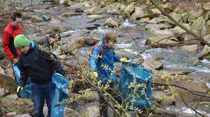 Jugendliche des Fischereivereins Ermstal befreien das Erms-Ufer bei der Neuhäuser Hofbühlhalle von Müll. FOTO: SANDER