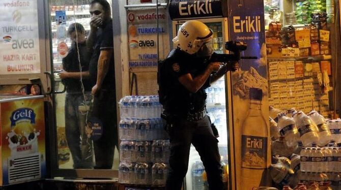 Ein Polizist feuert mit Plastikgeschossen auf Demonstranten. Foto: Sedat Suna