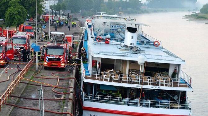 Feuerwehrleute pumpen Wasser aus dem Schiff, das mit Schlagseite am Kai liegt. Foto: Piroschka Van Der Wouw