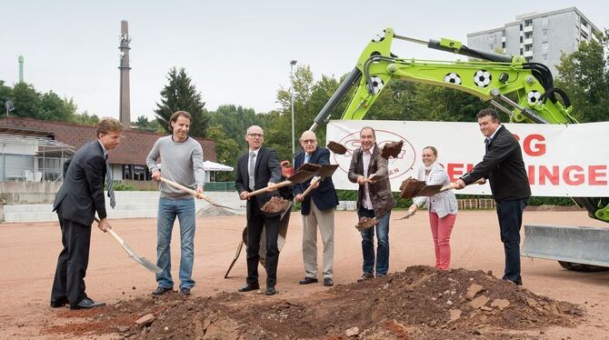 Vereinsmitglieder samt Geldgebern beim symbolischen Spatenstich auf dem alten Tennenspielfeld. Im Hintergrund rechts sind die Ho