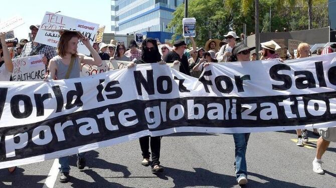 Trotz sengender Hitze haben sich am Rande des Gipfels ein paar hundert Demonstranten versammelt. Foto: Dave Hunt