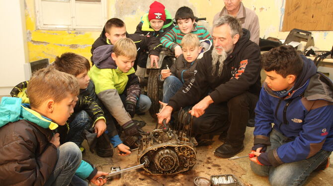 Dirk Hildebrandt (Zweiter von rechts) und seine Kids zerlegen in der neuen Schrauberwerkstatt einen alten Motor. FOTO: BAIER