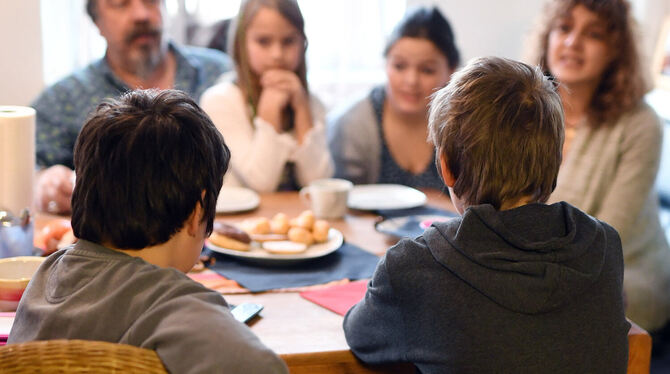 Eltern einer Bereitschaftspflegefamilie sitzen mit ihren Kindern Jana und Jenny und zwei Pflegekindern am Kaffeetisch.  FOTO: D