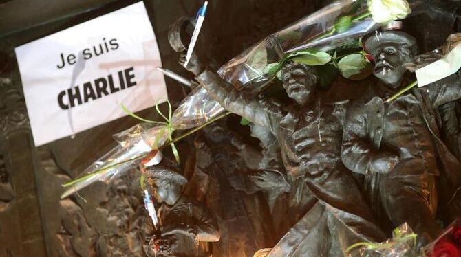 Trauernde in Paris haben ein Relief mit einem Schild »Je suis Charlie« (Ich bin Charlie), Blumen, Kerzen und einem Stift umge