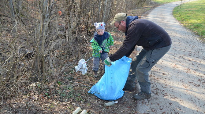 Benjamin Swatoch sammelt mit seinem Sohn Noah Müll für einen sauberen Wald bei der Waldputzete in Gomaringen.  FOTO: GOERLICH