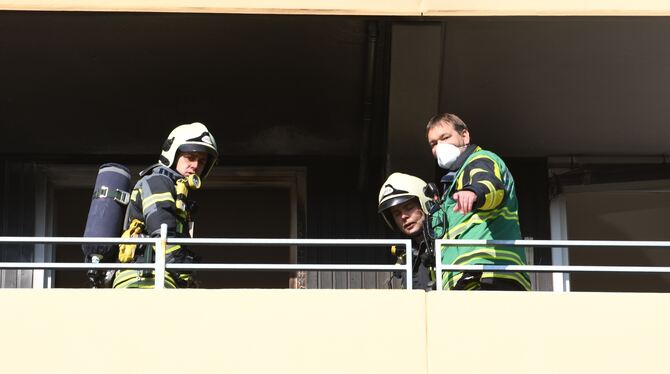 Einsatzkräfte auf dem stark durch den brennenden Campingstuhl in Mitleidenschaft gezogenen Balkon.