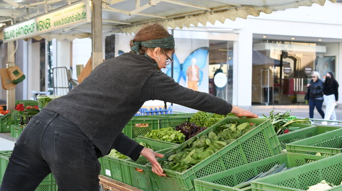 Christine vom Bioland Gärtnerhof Werner räumt eine Kiste frischen Spinat auf den Marktstand.