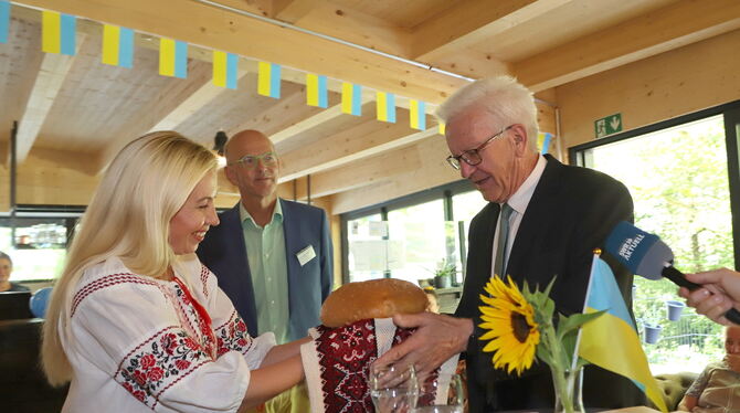 Die Ukrainerin Alla Didenko überreicht Ministerpräsident Winfried Kretschmann zur Begrüßung in Eningen einen Laib Brot. Hans-Jür