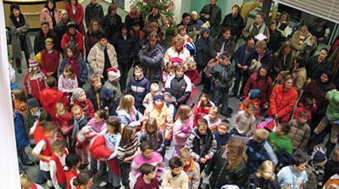 Münsinger Grundschulkinder wuseln zwischen vier Weihnachtsbäumen, für die sie den Schmuck selbst gefertigt haben.
GEA-FOTO: OEL