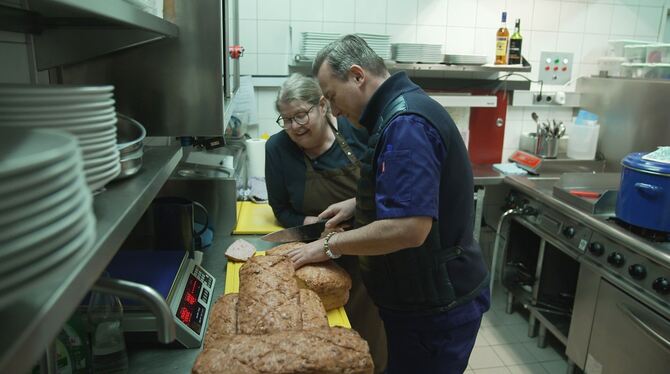 Marion Bosler und Tim Raue schneiden den selbst kreierten Leberkäse an.