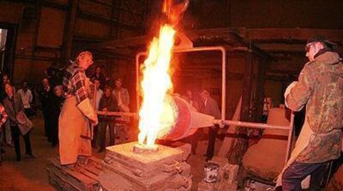 Flüssige Glocke: Josef Flier (links) und sein Sohn Jascha gießen die heiße Bronze in die Metallform. Die Sickenhäuser beobachten die nicht ganz ungefährliche Arbeit in sicherer Entfernung.
FOTO: REISNER