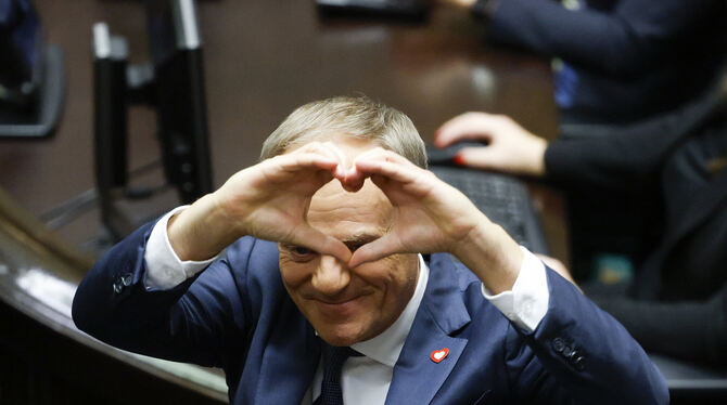 Donald Tusk formt nach seiner Wahl zum polnischen Premierminister im Parlament ein Herz mit seinen Händen.