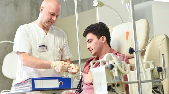 Ein Pfleger bereitet den Reutlinger Patienten Georgios Kessesidis in Heidelberg auf eine Krebsbehandlung vor.  FOTO: DPA