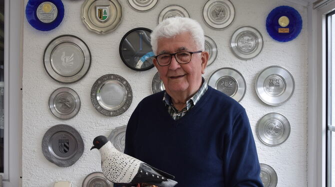 Walter Wagner vor einem kleinen Teil seiner Preise. In der Hand hält er die geschnitzte Figur einer Silberschuppen-Taube.