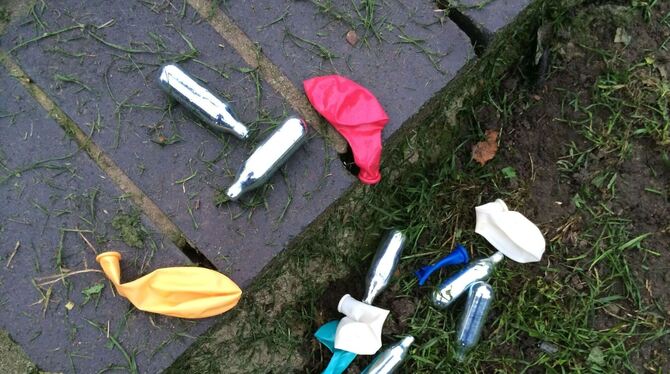 Weggeworfene Lachgas-Kartuschen und Luftballons liegen in einem Park.