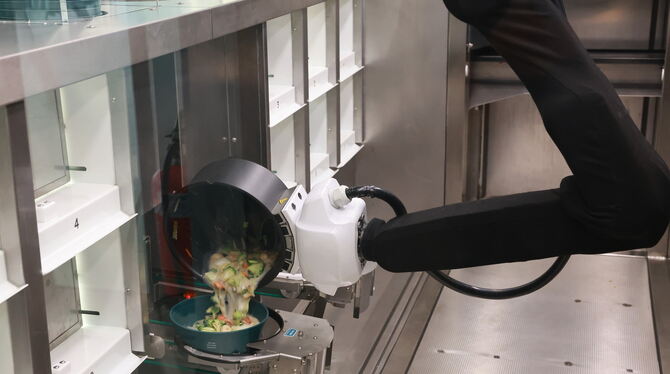 Ein Roboterarm kippt thailändische Suppe in eine Schüssel. Wenn das Gericht servierfertig ist, wird es aus einer Klappe herausge