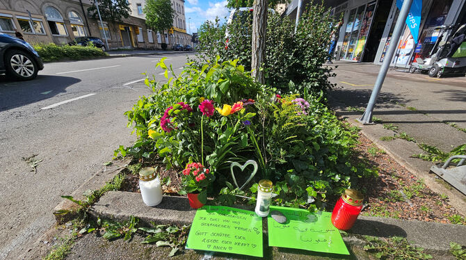 Blumen und Grablichter liegen und stehen an der Stelle in der Bahnhofstraße, wo am Sonntag zwei Menschen bei einem Unfall an ein