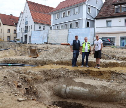 Bürgermeister Andreas Schmidt (von links), Ingenieur Gerhard Lutz und Archäologe Sören Frommer vor der Baugrube auf dem kleinen 