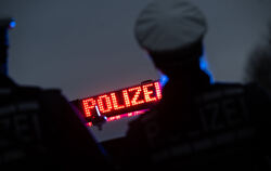 Zwei Polizisten stehen vor einem Polizeifahrzeug (Symbolbild). 