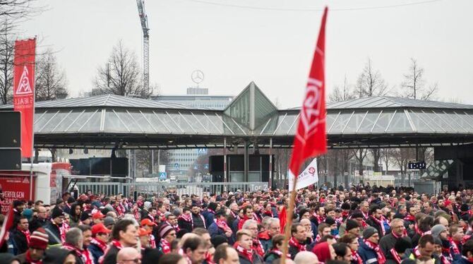 Demonstranten stehen während eines Warnstreiks der Gewerkschaft IG Metall vor dem Mercedes-Benz-Werk in Untertürkheim. Foto: