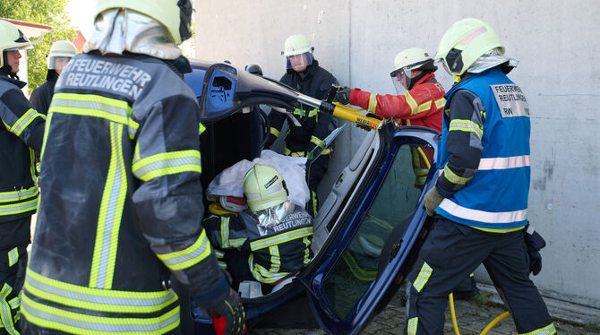 Die Feuerwehr-Auszubildenden  retten einen Dummy aus einem Unfall-Auto.