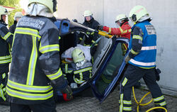 Die Feuerwehr-Auszubildenden  retten einen Dummy aus einem Unfall-Auto.