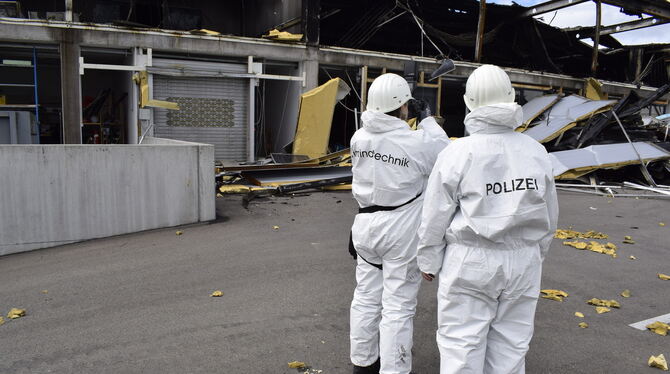 Zwei der Brandermittler vom Polizeipräsidium Reutlingen machen Aufnahmen vom Außerbereich der nahezu vollständig zerstörten Lage