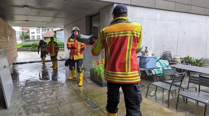 Das Wasser der Echaz kommt bis ans Haus. Die Feuerwehr Pfullingen ist zur Stelle und legt Sandsäcke mittels einer Kette.