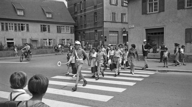 Das Motiv für den Monat Juni 2025: Viel los am Zebrastreifen in der Großen Heerstraße im Jahre 1963. Schülerlotsen bringen die W