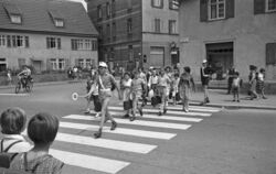 Das Motiv für den Monat Juni 2025: Viel los am Zebrastreifen in der Großen Heerstraße im Jahre 1963. Schülerlotsen bringen die W