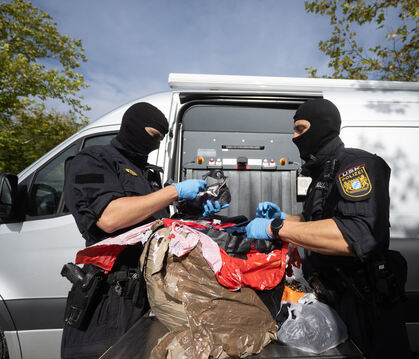 Bayrische Polizisten kontrollieren am Tag der Großrazzia Pakete, die in einem Lastwagen am Stadion Kreuzeiche sichergestellt wur