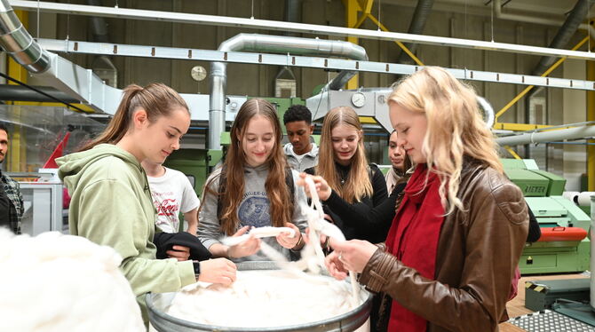 Gymnasiasten in der Maschinenhalle der Hochschule Reutlingen: Von Hand zu Hand wandern Baumwollflocken, dann die dickeren Karden