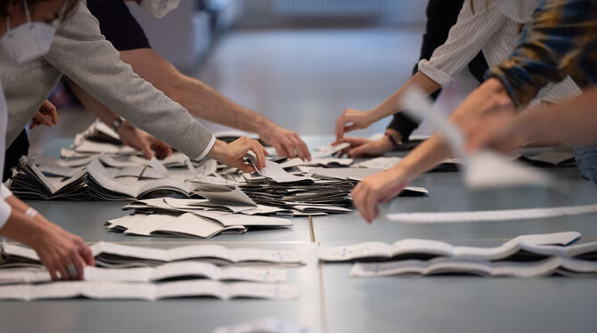 Wahlhelfer und Wahlhelferinnen zählen in einem Wahllokal Stimmzettel für die Bundestagswahl.