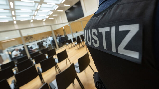 Ein Justizbeamter steht in einem Saal des Oberlandesgerichts Stuttgart. Die Raumteiler bestehen aus kugelsicherem Glas, immerhin